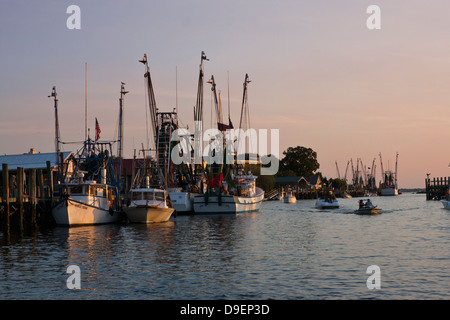 Die Sonne geht auf der aktiven Uferpromenade entlang Shem Creek, Mount Pleasant, South Carolina, USA in ein warmes Licht baden. Stockfoto