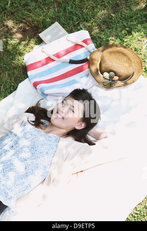 Junge Frau, die Verlegung auf Grünland lächelnd Stockfoto