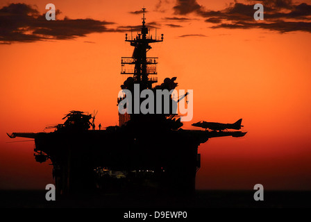 Die untergehende Sonne Silhouetten der amphibischen Angriff Schiff USS Makin Island. Stockfoto