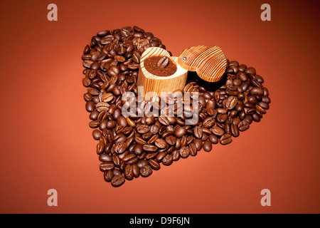 Herzen von frisch gerösteten Kaffeebohnen mit einer Holzkiste, Herzen von frisch gerösteten Kaffeebohnen mit einem KUGELPUNZEN aus Holz Stockfoto