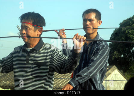 Schmerzhafte Folk Art A besondere Volkskunst Aktivität ist in Ding'an von Haikou, Provinz Hainan, China statt. Die ausführenden durchbohren ihre Wangen mit schweren Eisenstangen und schieben Sie sie auf der anderen Seite ihre Mundwinkel. Die atemberaubende Performance zieht mehr als 10.000 Zuschauer. Sobald die Darsteller Verstümmelung selbst beendet haben, sie entziehen die Eisenstangen und müssen schnell Stockfoto