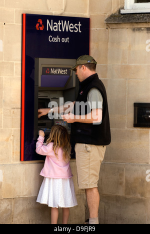 Mann mit junger Tochter mit Natwest Cashpoint Maschine, Petersfield, Hampshire, UK. Stockfoto