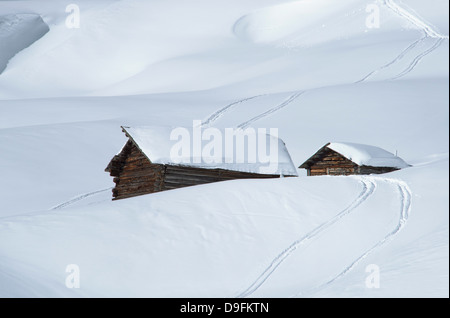 Zwei alte hölzerne Scheunen, umgeben von tiefen Schnee und Ski Tracks in den Dolomiten, Südtirol, Italien Stockfoto