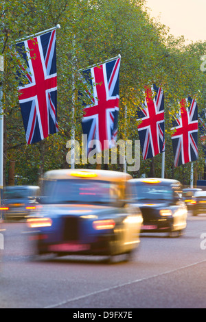 Schwarze Taxis entlang der Mall mit Union Jack-Flaggen, London, England, UK Stockfoto