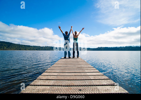 Paar auf einem Steg am See zeichnet, West Coast, Südinsel, Neuseeland Stockfoto