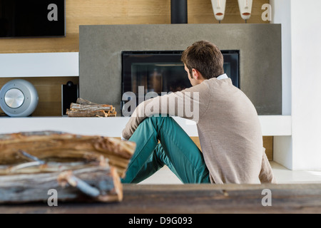 Mann sitzt vor einem Kamin zu Hause Stockfoto
