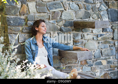 Frau lehnte sich gegen eine Steinmauer und Tagträumen Stockfoto
