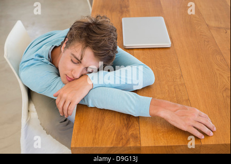 Erhöhte Ansicht eines Mannes Nickerchen auf einem Tisch mit einem laptop Stockfoto