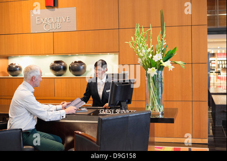 Unternehmer im Gespräch mit Empfangsdame an der Hotel Rezeption Theke Stockfoto