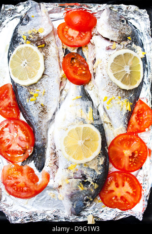 Frische Goldbrasse mit Zitrone, Tomaten und Gewürzen kochen Folie Stockfoto