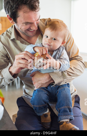 Mann, die Verfütterung von Brot an seinen Sohn auf eine Küchentheke Stockfoto
