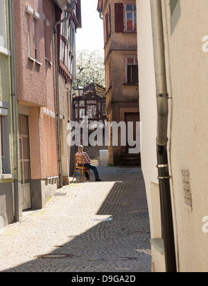 MOSBACH, Deutschland - April 25: Alter Mann ruht auf Stuhl in engen Straße von Mosbach in Süddeutschland am 25. April 2013. Stockfoto