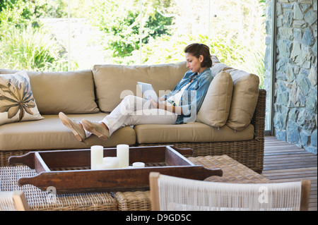 Frau auf einem Sofa liegend und mit einer digital-Tablette Stockfoto