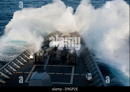 Der Bug der USS Cowpens pflügt durch eine Welle in rauer See. Stockfoto