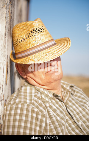 Senior woman nehmen eine Siesta in der Sonne des Mittelmeers mit seinem Strohhut Abschirmung seine Augen. Stockfoto