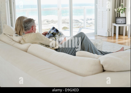Paar auf einer Couch sitzen und Lesen einer Zeitschrift Stockfoto