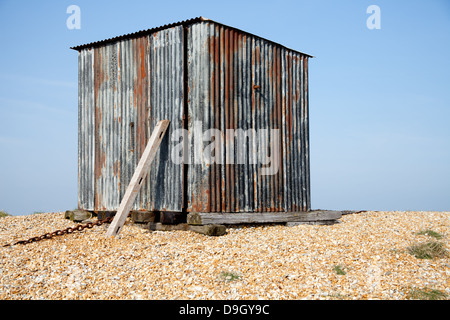 Schuppen/Metallbehälter am Kiesstrand vor einem strahlend blauen Himmel. Stockfoto