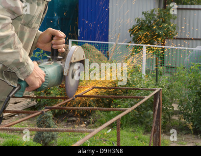 Winkel-Schleifer Metall Sägen mit blinkenden Funken hautnah und Mechaniker Hände Hauptreparatur Garten Sommer Arbeitszeit Stockfoto