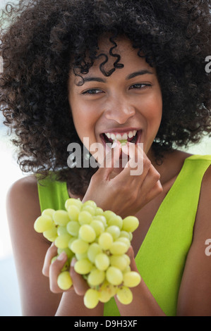 Lächelnde Frau essen Trauben Stockfoto