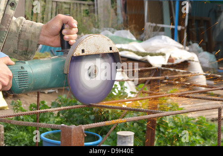 Winkel-Schleifer Metall Sägen mit blinkenden Funken hautnah und Mechaniker Hände Hauptreparatur Garten Sommer Arbeitszeit Stockfoto