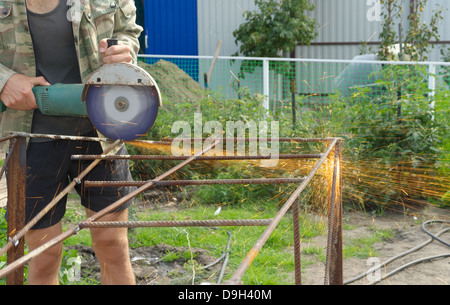 Winkel-Schleifer Metall Sägen mit blinkenden Funken hautnah und Mechaniker Hände Hauptreparatur Garten Sommer Arbeitszeit Stockfoto