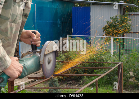 Winkel-Schleifer Metall Sägen mit blinkenden Funken hautnah und Mechaniker Hände Hauptreparatur Garten Sommer Arbeitszeit Stockfoto