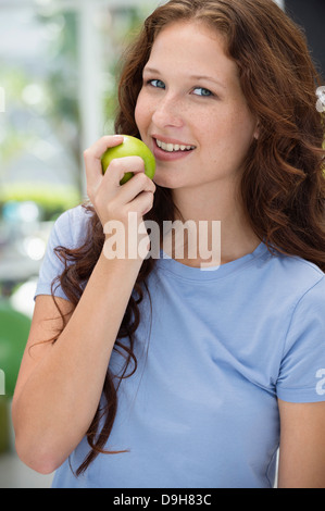 Frau einen grünen Apfel zu essen und lächelnd Stockfoto