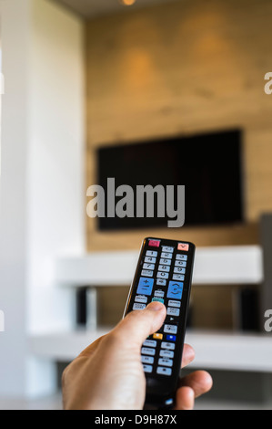 Person die Hand eine TV-Fernbedienung in Betrieb Stockfoto