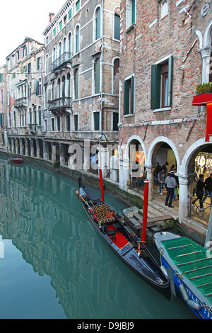 Gondeln und Gondolieri auf einer kleinen Nebenstraße Canal mit bunten Altbauten und hölzernen Liegeplatz Beiträge Venedig im winter Stockfoto