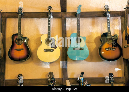 Vier bunte Epiphone und Fender Akustikgitarren hängen an der Wand von einem malerischen Musikgeschäft in Micanopy, Florida. Stockfoto