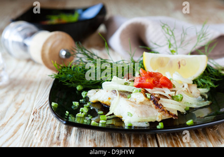 Gebratener Fisch auf einem schwarzen Teller, Essen Stockfoto