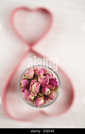 Rose Tee Knospen in Glas und Herz Formschneiden auf Hintergrund, flachen dof Stockfoto