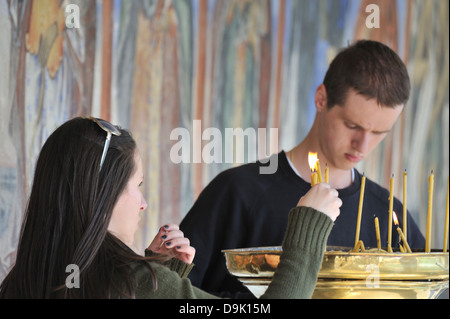 Junge Menschen Beleuchtung Votiv-Kerzen und Sveti Jovan Bigorski Kloster, Mavrovo, Mazedonien Stockfoto