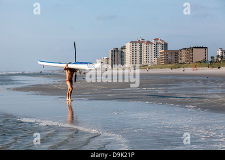 Männlichen Konkurrenten tragen seine Seekajak aus dem Meer vor der 4. jährlichen JAX Beach paddeln Challenge. Stockfoto