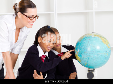 elementare Geografielehrer und Studenten auf der Suche im Globe im Klassenzimmer Stockfoto
