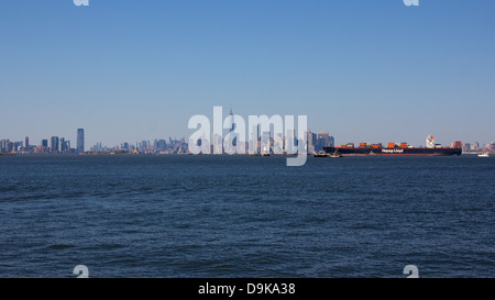 NEW YORK, NY, USA - 27. Mai 2013: Ein deutscher Containerschiff vor der Kulisse der Skyline von Manhattan in New York City kommt. Stockfoto