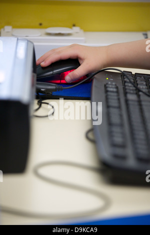 Primäre UK Schulkind hält eine Maus in einer IKT-Suite in Nahaufnahme Stockfoto