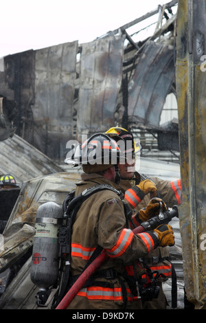 Zwei Feuerwehrleute umgeben von Schutt aus einem Gebäudebrand Stockfoto