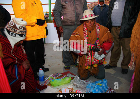 LA PAZ, BOLIVIEN, 21.. Juni. Ein männlicher Aymara amauta oder spiritueller Führer segnet einen toten Lamas-Fus (lokal Sullu genannt), während er ein spezielles Angebot namens mesa blanca für eine Veranstaltung zur Feier des Aymara-Neujahrs oder Willka Kuti (auch die Wintersonnenwende) vorbereitet. Der Sonnenaufgang markiert den Beginn des neuen Jahres (5521 im Aymara Kalender). Der Schamane auf der linken Seite trägt einen typischen Wollhut mit Ohrenklappen, den chullo/Chullu genannt. Kredit: James Brunker / Alamy Live Nachrichten Stockfoto