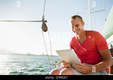 Junger Mann auf Yacht mit digital-Tablette Stockfoto
