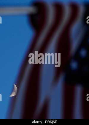 Der partielle Mond scheint durch eine Fahne hängen von einem Laternenmast in der Innenstadt von Vernon, Alabama. Stockfoto