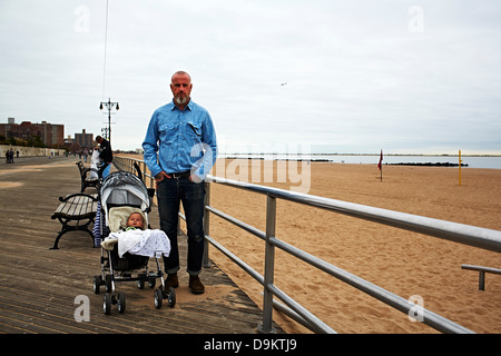 Mann mit Baby im Kinderwagen am Meer Stockfoto