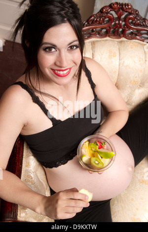 Schöne Frau 8 Monate plus schwanger ihre Füße etwas Obst zu essen Stockfoto