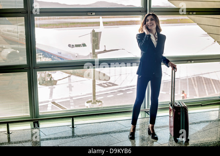 Junge Frau am Handy in Flughafen Stockfoto