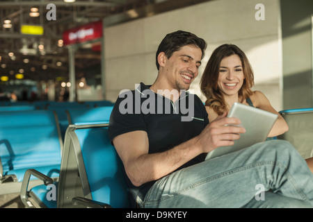 Junges Paar mit digital-Tablette in Flughafen-Abflug-lounge Stockfoto