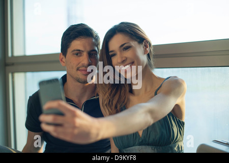 Junges Paar fotografieren sich auf Smartphone in Flughafen Stockfoto