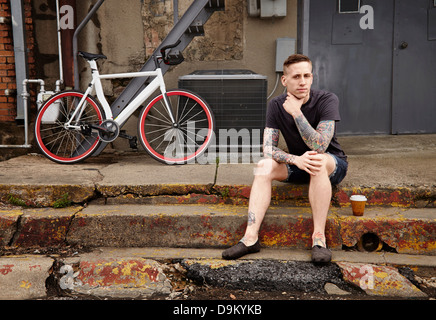 Porträt des jungen tätowierte Mann auf Treppe Stockfoto