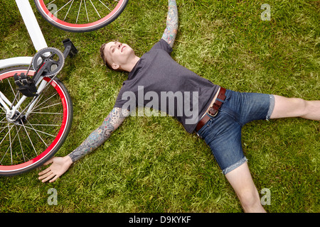 Junge tätowierte Mann auf dem Rasen liegend Stockfoto