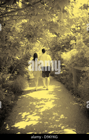 Young Caucasian paar zu Fuß entlang eines Baumes gesäumten Pfad Stockfoto