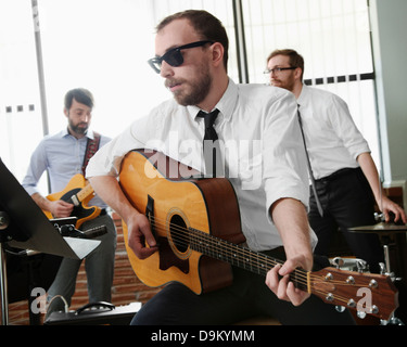 Junger Mann spielt Gitarre im Proberaum Stockfoto